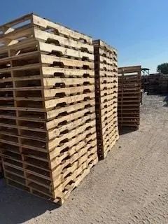Tall stacks of used wooden pallets in the yard